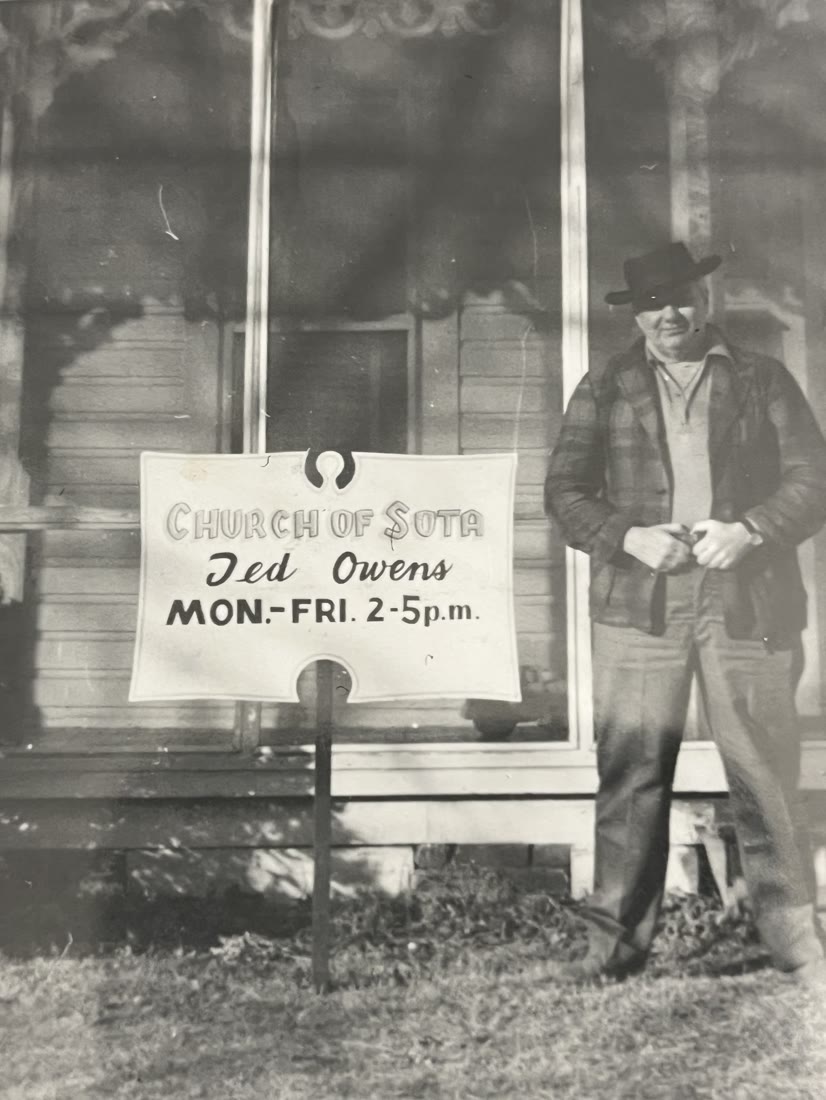 Ted Owens standing beside a hand-painted sign reading Church of SOTA, Ted Owens, Mon-Fri 2-5 p.m.